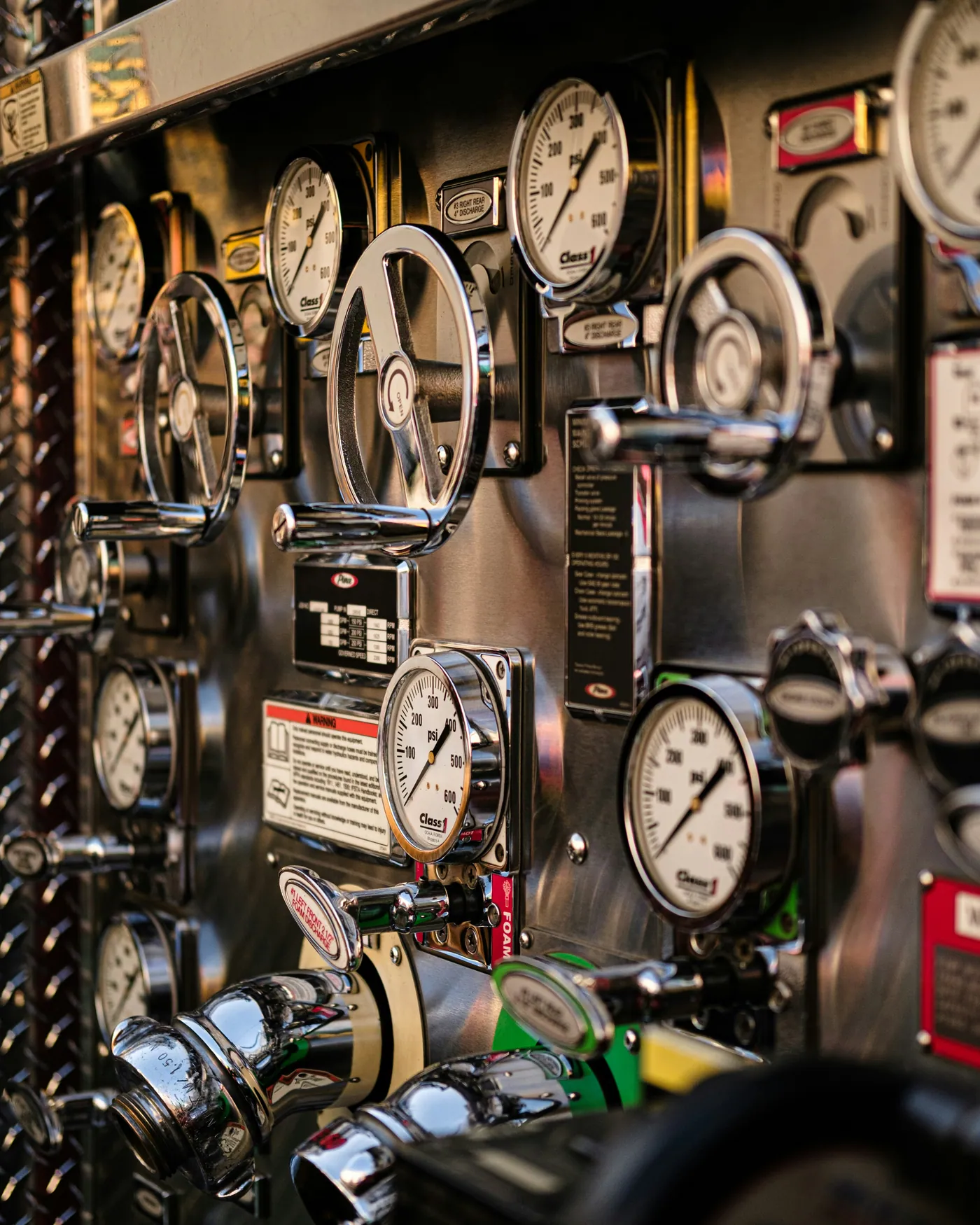 Close-up of a pump control panel with pressure gauges, chrome handwheel valves and discharge outlets